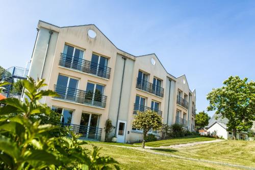an apartment building with balconies on a lawn at Logis L'Ermitage Hôtel & Restaurant in Saulges
