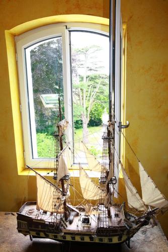 a model ship sitting in a window in a room at Le Domaine Du Lieu Athan ,réservé aux adultes in Saint-Gâtien-des-Bois