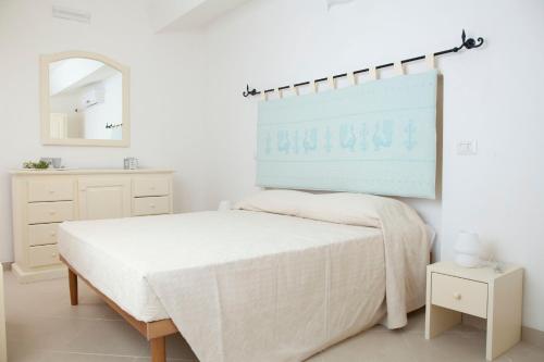 a white bedroom with a bed and a mirror at Via dei Mari Guest House in Oristano