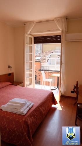 a bedroom with a bed and a view of a balcony at Hotel Mimosa in Spotorno