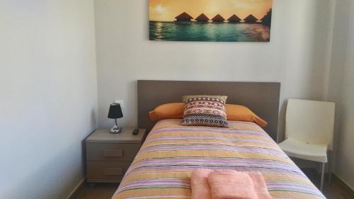 1 dormitorio con 1 cama, mesita de noche y una foto en Casa Txema en Lorca