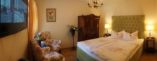 a bedroom with a bed and two chairs and a television at Hotel Villa Herzog in Dresden