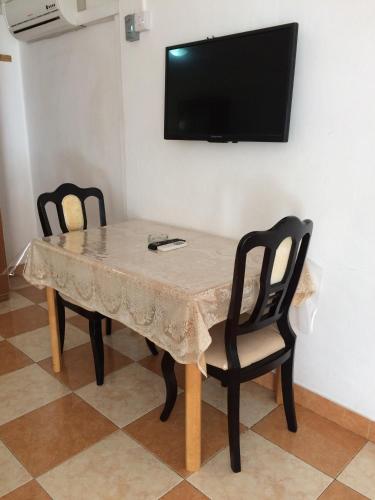 a table with two chairs and a television on a wall at Ebrahim Flats - Grand Baie Beach in Grand Baie