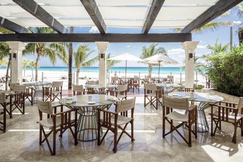 een restaurant met tafels en stoelen op het strand bij Royal Hideaway Playacar All-Inclusive Adults Only Resort in Playa del Carmen