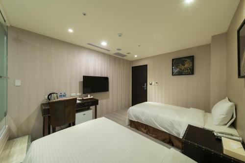 a hotel room with two beds and a television at XinsheHotel - Chungli in Zhongli