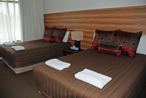 a hotel room with two beds and a large headboard at Red Cedars Motel in Canberra
