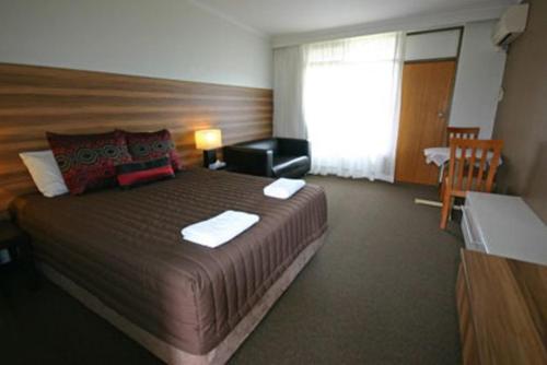 a hotel room with a large bed and a window at Red Cedars Motel in Canberra