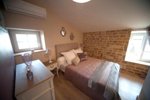 a bedroom with a bed and a brick wall at Le Petit Nid*** in Amance