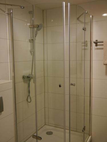 a shower with a glass door in a bathroom at Ruhrstadtarena Hotel in Herne