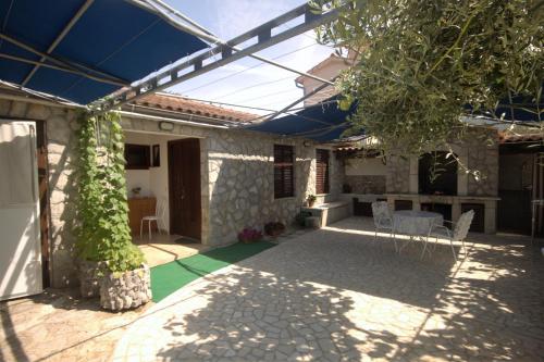a patio with a table and chairs under a pergola at Apartments Cvelic Milovcic in Malinska
