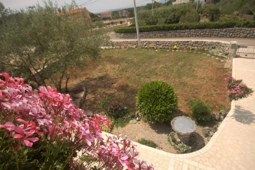 a garden with pink flowers and a stone wall at Apartments Cvelic Milovcic in Malinska