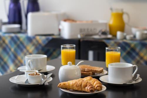 een tafel met borden en kopjes sinaasappelsap bij Hostel & Suites del Rio in Colonia del Sacramento