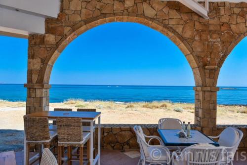 a patio with tables and chairs and a view of the ocean at Pyrgos Blue in Malia