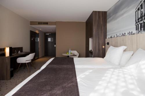 a hotel room with a large bed and a desk at Mercure Blankenberge in Blankenberge