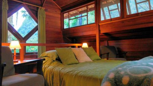 1 dormitorio con 1 cama en una habitación con ventanas en Eco Resort Nagual en São Pedro da Serra