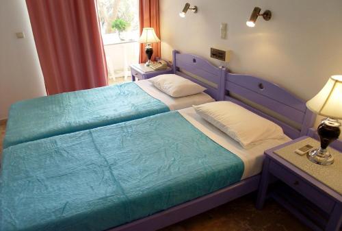 um quarto com uma cama azul e 2 almofadas em Doreen Suites em Kalamaki
