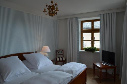 sypialnia z łóżkiem, telewizorem i oknem w obiekcie Alte Posthalterei Zorneding w mieście Zorneding