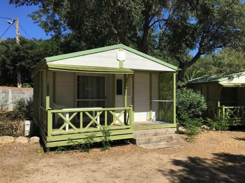 a small green shed with a porch in a yard at Camping Pezza Cardo in Porto-Vecchio