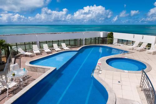 a swimming pool on top of a building with the ocean at Best Western Premier Maceió in Maceió