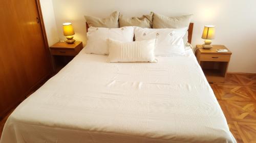 a large white bed with two lamps on two tables at Centar old town, with parking place in Pula