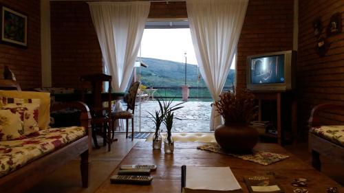 a living room with a couch and a tv at Pousada Quinta do Barao in Conceição da Ibitipoca