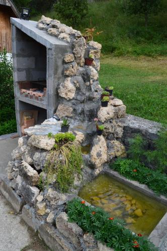 a stone wall with a pond in a garden at Apartment Sijakovic in Mokra Gora