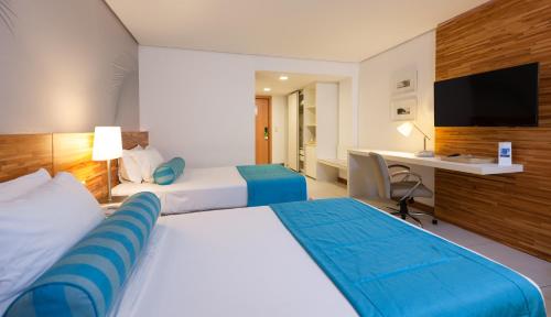 a hotel room with two beds and a desk at Best Western Premier Maceió in Maceió