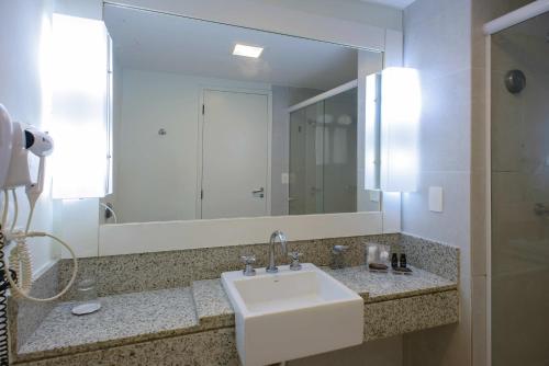 baño con lavabo y espejo grande en Del Mar Hotel, en Aracaju