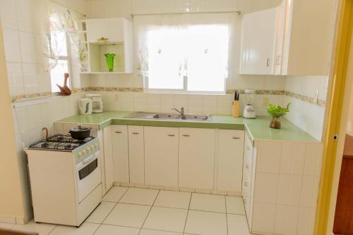 a white kitchen with a stove and a sink at The Lush in Willemstad