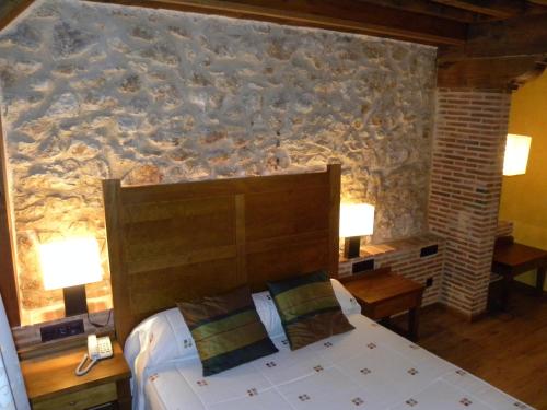 a bedroom with a bed and a stone wall at Posada Los Templarios in Ucero