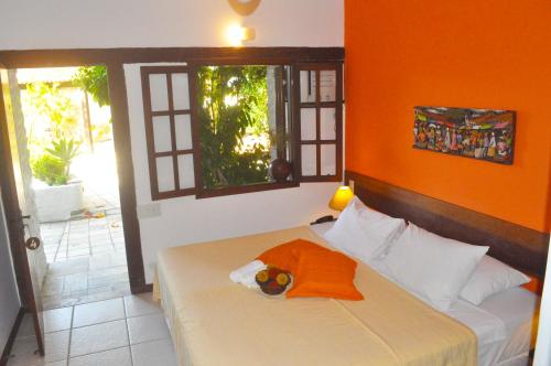 a bedroom with a bed with an orange wall at Pousada Caminho do Sol in Arraial do Cabo