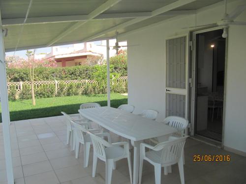 una mesa blanca y sillas en un patio en villetta al mare punta braccetto en Punta Braccetto