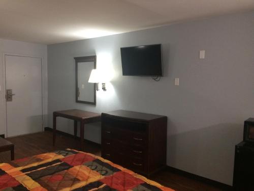 1 dormitorio con 1 cama y TV en la pared en Gulf American Inns, en Decatur