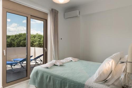 a bedroom with a bed and a balcony with a chair at Niovi Seaside Suites in Kissamos