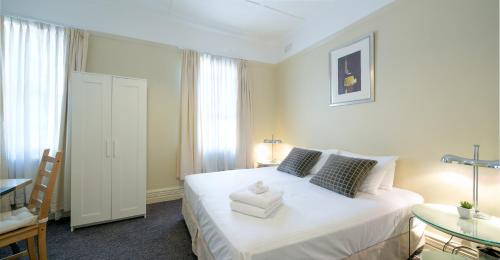 a bedroom with a large white bed and a table at Neutral Bay Lodge in Sydney