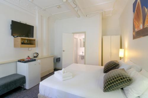 Habitación de hotel con cama blanca y TV en Neutral Bay Lodge, en Sídney