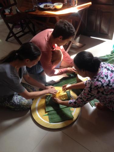a group of people standing around a table with a cake at The Purple Hue Homestay in Hue