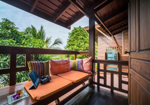 a bench on a porch with a laptop on it at Pukha Nanfa Hotel in Nan