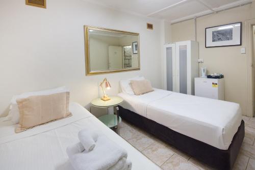 two beds in a room with a mirror at Neutral Bay Lodge in Sydney