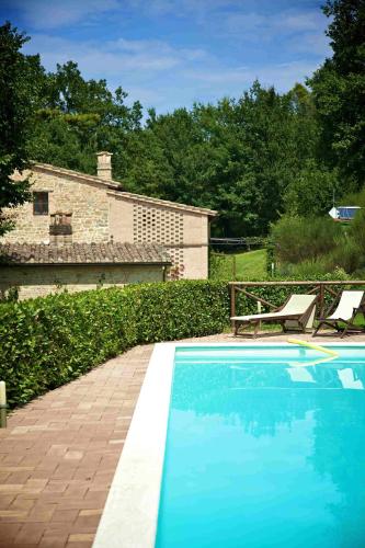 a blue swimming pool with a bench next to a house at Hotel & SPA L'Antico Forziere in Deruta