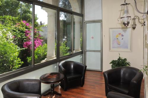 two chairs and a table in a room with windows at The Little House In Bakah in Jerusalem