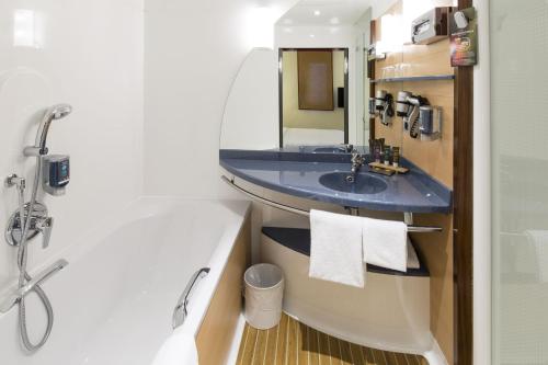 a bathroom with a blue sink and a shower at Novotel Suites Hannover in Hannover