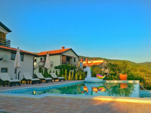 a house with a swimming pool with chairs and a house at Home Andrea with infinity salty pool in Roč