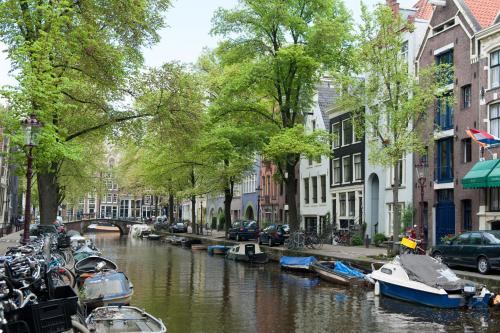 a canal in a city with boats and buildings at Artis Plantage Apartment in Amsterdam