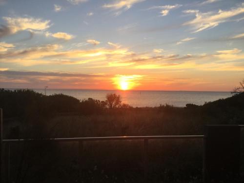a sunset over the water with the sun in the sky at Beachside Apartments Bonbeach in Bonbeach