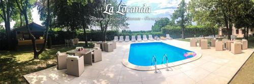 a swimming pool in a yard with chairs and a table at La Locanda in Aviano