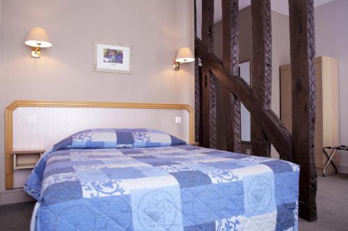 a bedroom with a bed with a blue and white blanket at Hôtel du Cheval Rouge in Versailles