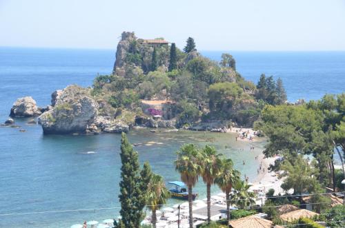 a beach with palm trees and a rocky island at Gole Dell'Alcantara Villa Lucia in Motta Camastra