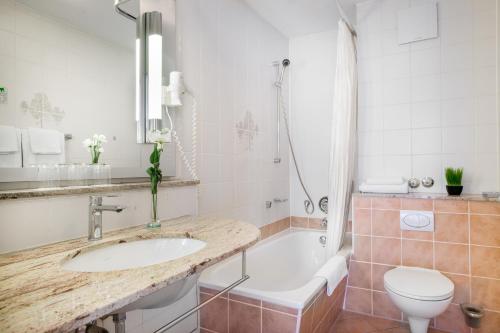 a bathroom with a sink and a tub and a toilet at Hotel Rega Stuttgart in Stuttgart
