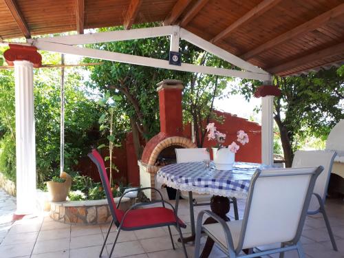 a table and chairs on a patio with a fireplace at Villa PANGALIS Romantica in Kato Pavliana